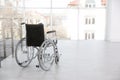 Modern wheelchair in empty room, space for text. Medical