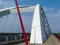 modern white basket handle arched steel cable suspension bridge. red steel street lights.