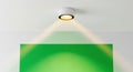 Modern White Ceiling Spotlight Illuminating Vibrant Green Gradient Panel with Visible Warm Light Beam Royalty Free Stock Photo