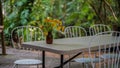 Modern white chair and table set up in the garden. Dining table in the outdoor garden decorated with yellow flower poppies in a