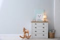 Modern white chest of drawers near light wall in child room, space for text. Interior design Royalty Free Stock Photo