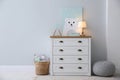 Modern white chest of drawers near light wall in child room, space for text. Interior design Royalty Free Stock Photo