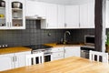 Modern white color home kitchen corner with solid natural color oak wood countertop.