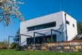 Modern, white, cube, elegant, minimalist style passive house with large panoramic windows, grey shutters in maintained garden. Royalty Free Stock Photo