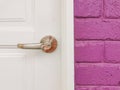 Modern white door with chrome door handle and purple wall bricks Royalty Free Stock Photo