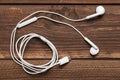 Modern white earphone, white in ear headphone on wooden table. White earphones over wooden board Royalty Free Stock Photo