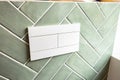 A modern white flush plate for a concealed installation system against a green tile background. This bathroom design is suitable Royalty Free Stock Photo