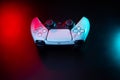 Modern white gamepad illuminated in red and blue. Game controller for video games and e-sports on a dark back