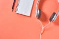 Modern white headphones with cable near blank paper notebook and pencil on orange background Royalty Free Stock Photo