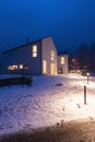 Modern white house with light windows surronded by mountain, snow and trees. Chirstmas mood