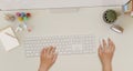 Modern white office desk workspace with a female hands typing on a computer keyboard. top view Royalty Free Stock Photo