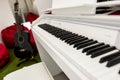 Modern, white piano keyboard in focus, black guitar and red beanbags in the background. Royalty Free Stock Photo