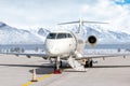 Modern white private jet with an opened gangway door at the winter airport apron on the background of high mountains Royalty Free Stock Photo