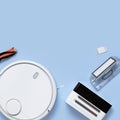 Modern white robot vacuum cleaner, filter, brush on blue background flat lay. New technologies, quick house cleaning, automatic