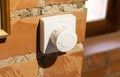 Modern white room and floor heating controller on a brick wall, close-up. Adjustment of the comfortable temperature in the room