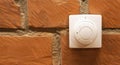 Modern white room and floor heating controller on a brick wall, close-up. Adjustment of the comfortable temperature in the room.