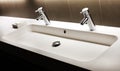 Modern white sink with two shining faucets, tap