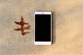 Modern white smartphone, cell phone with blank black display on table. Golden marble background with dry oak leaf