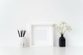 Modern white square frame mockup with a Aegopodium in black vase and black pencils on white background.