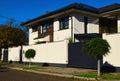 Modern white stucco finished house with solid white fence and small evergreen trees