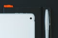 Modern white tablet, notebook and pen over black background. Electronic devices. Flat view of gadget Royalty Free Stock Photo