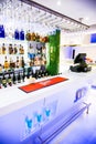 Modern, white-themed bar filled with bottles of wine and glasses illuminated by bright lights