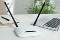 Modern wi-fi router and laptop on white table indoors Royalty Free Stock Photo