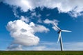 Modern wind turbine against a beautiful blue sky with white, fluffy clouds in the background Royalty Free Stock Photo