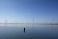 Modern windmills in the water near the shore along a green grassy dike Royalty Free Stock Photo