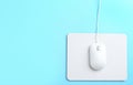 Modern wired mouse and white pad on blue background, top view. Space for text Royalty Free Stock Photo
