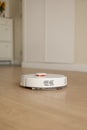 Modern wireless autonomous robotic vacuum cleaner cleans living room. Smart self-propelled white cleaning robot washes