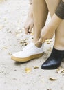 Modern woman is changing her shoes for sneakers on park, female feet