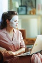 Modern woman with facial mask using website on laptop Royalty Free Stock Photo