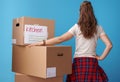 Modern woman standing next to cardboard boxes on blue Royalty Free Stock Photo