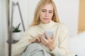 Modern woman surfing internet on phone, resting on sofa Royalty Free Stock Photo