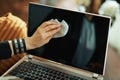 Modern woman wiping laptop display with cleaning cloth