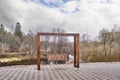 Modern wooden bench swinging on iron chains on embankment of Luga River, Russia.