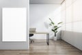 Modern wooden and concrete office interior with blank white mock up poster, workplace desk, laptop, chair, decorative plant, Royalty Free Stock Photo