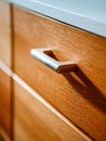 Modern wooden drawer with sleek metallic handle casting a soft shadow under natural light on smooth textured surface in a Royalty Free Stock Photo
