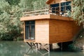 Modern wooden loft house on the lake, close-up. Exterior of a country house with a balcony, cottage on the water near the forest