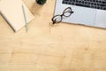 Modern wooden office desk table with laptop computer, succulent plant, paper notepad, pen. Top view with copy space, flat lay.