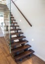 Modern wooden staircase with large thick glass balustrade