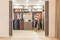 Modern wooden wardrobe with clothes hanging on rail in walk in closet Royalty Free Stock Photo