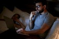 Modern Workaholic-Businessman lying on bed and working with laptop late at night