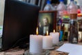 Modern workplace of a magician, sorcerer, psychologist. Three lighted white candles. Icons, laptop, water bottles in the blurry