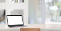 Modern workplace with open blank screen laptop computer on empty white wooden desk with blurred office Royalty Free Stock Photo