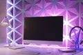 A modern workspace with a computer monitor, keyboard, mouse, lamp, headphones, and notebook, featuring purple geometric wall Royalty Free Stock Photo
