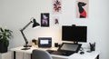 Modern workspace with computer monitors, desk lamp, and artistic wall decor. concept of home office, creative environment Royalty Free Stock Photo