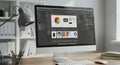 Modern workspace featuring a desktop computer displaying graphic design software Royalty Free Stock Photo