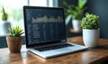 modern laptop displaying financial data and bar charts on screen placed on wooden desk with green plants in office environment Royalty Free Stock Photo